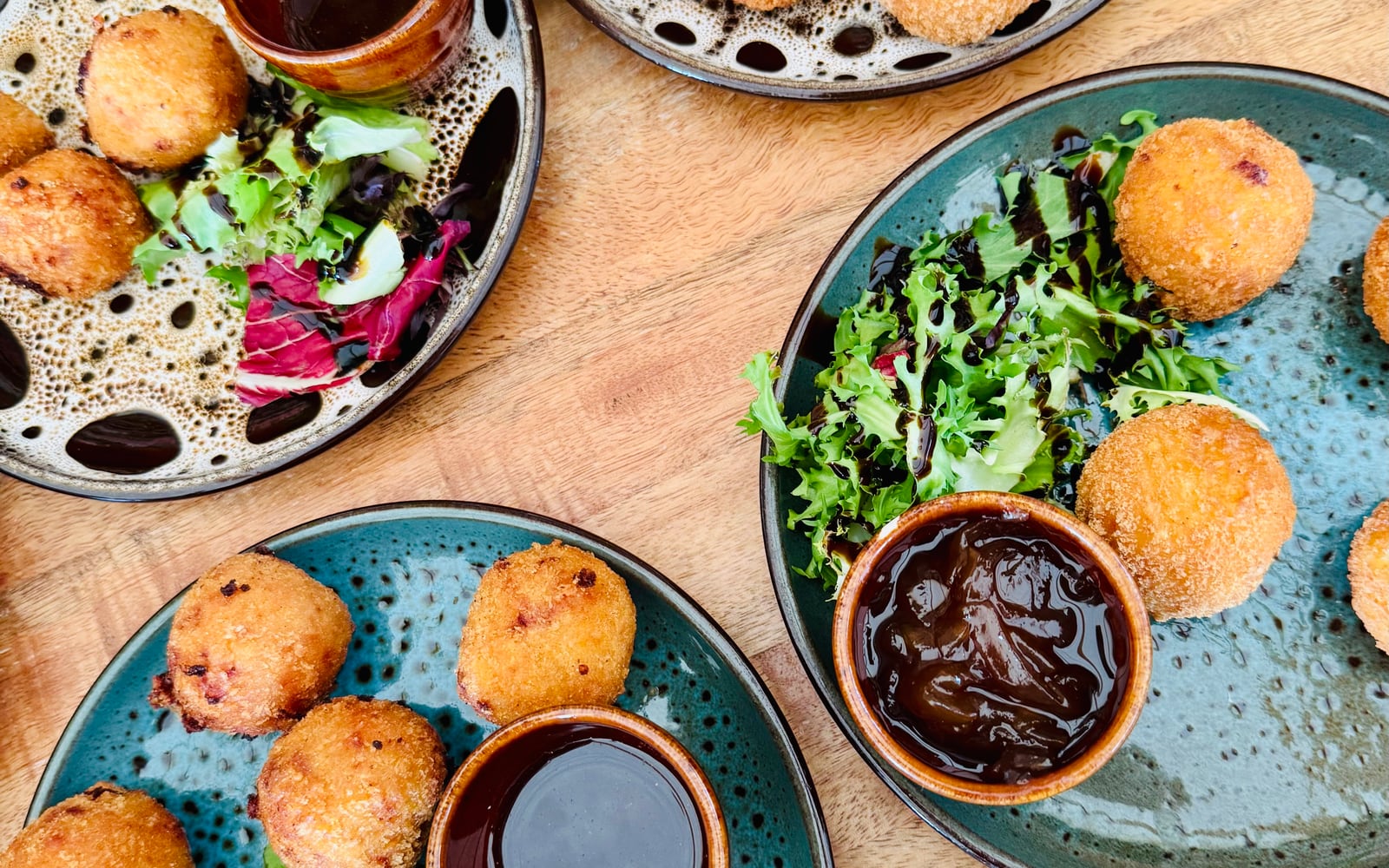 Golden crumbed croquettas with a dipping sauce and salad garnish at The Bank at Bude