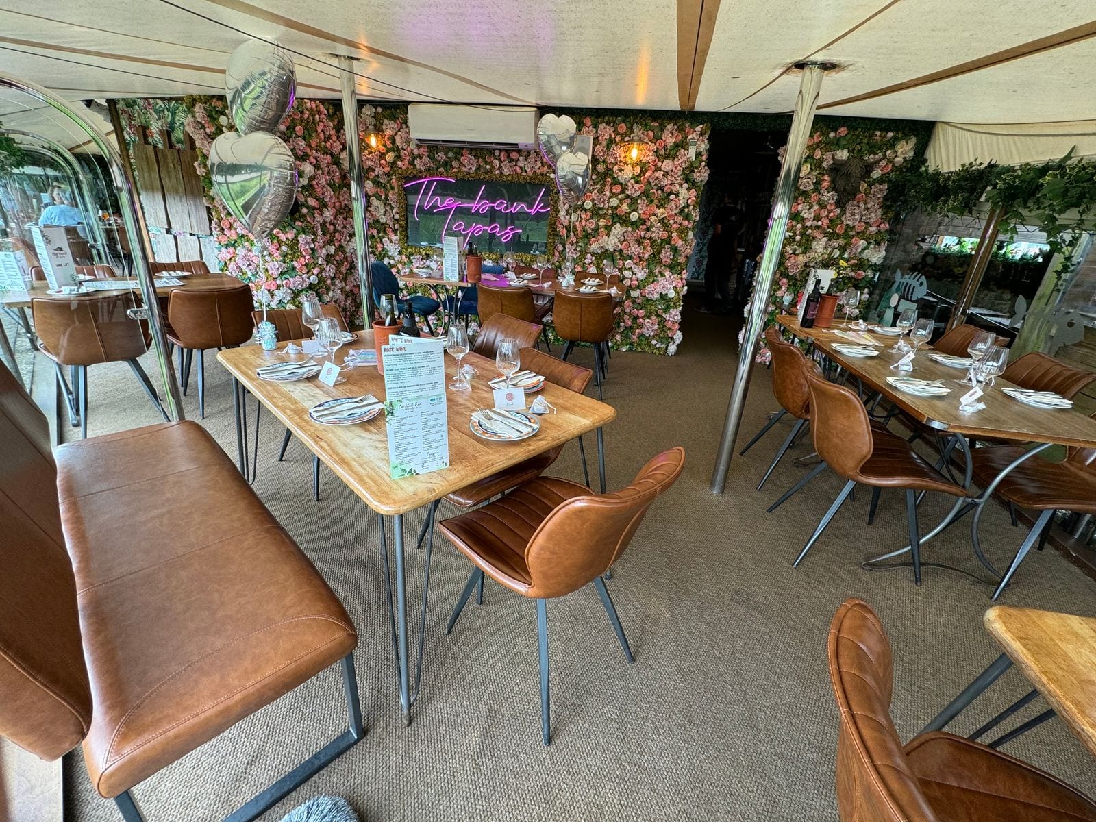 The Bank at Bude dining room dressed for a private event, with tables set beneath the pink-neon floral wall
