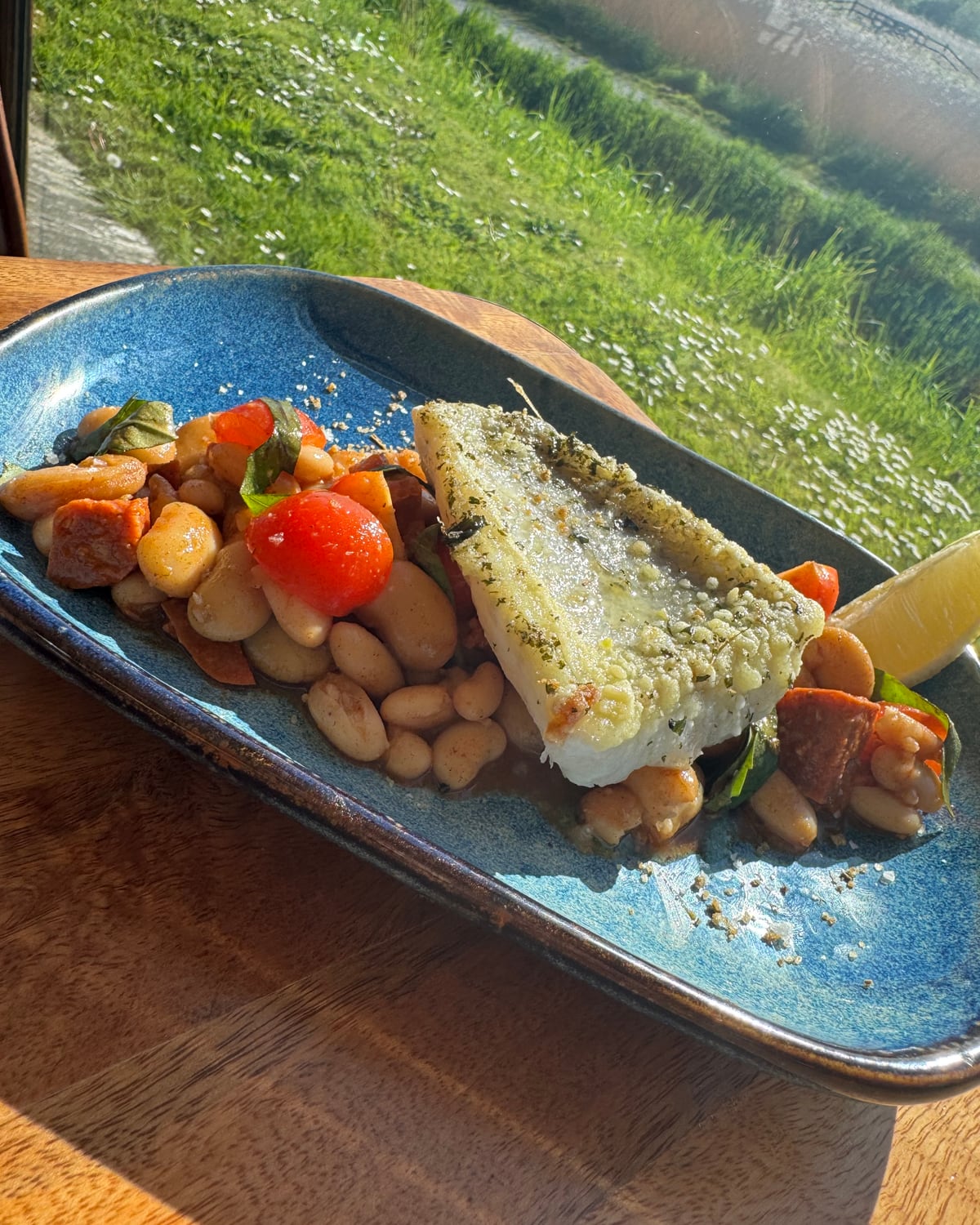 Oven-baked seabass on butter beans with chorizo and cherry tomato by the marsh-view window at The Bank at Bude